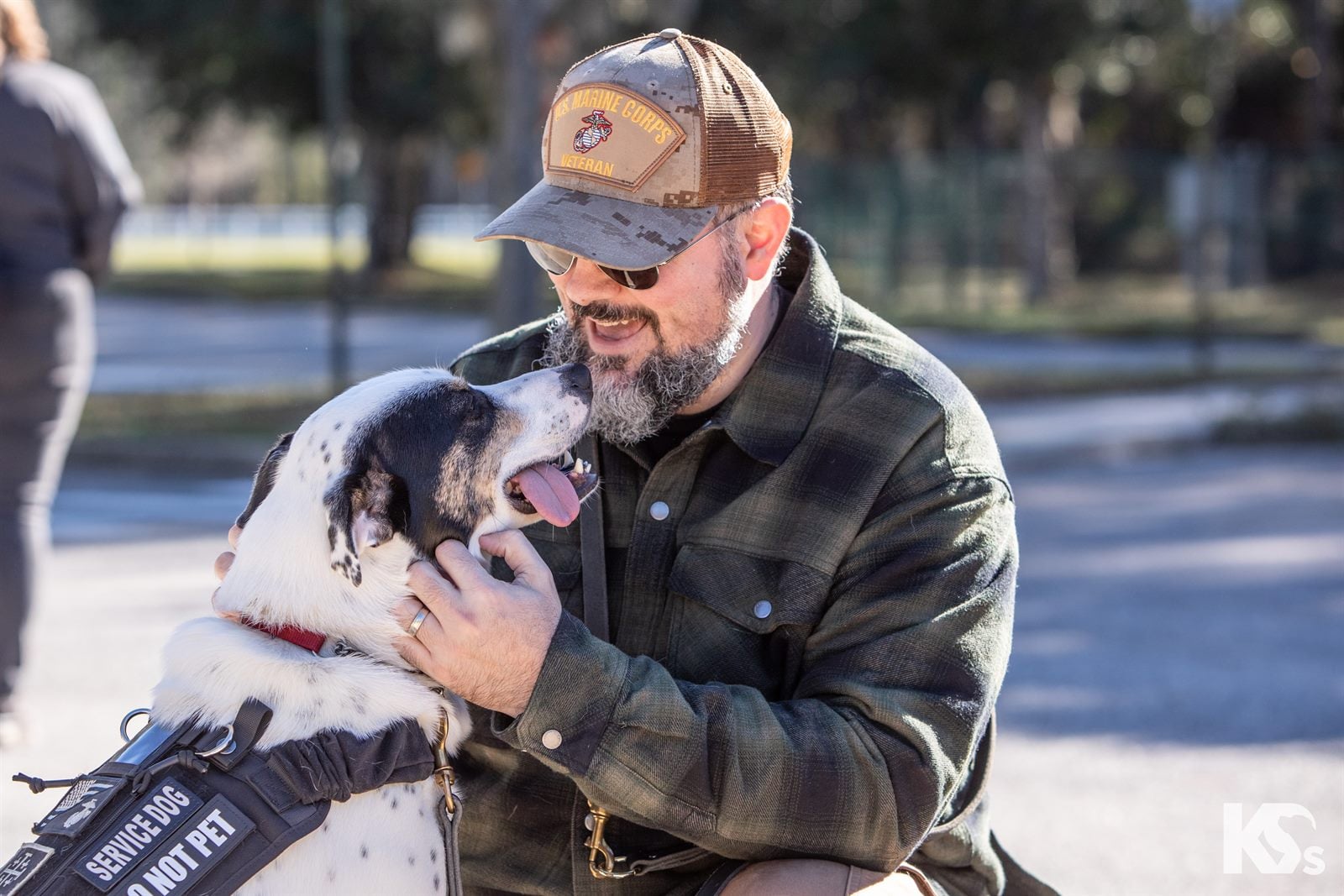 A Veteran smiling as his Service Dog leans in close to his face.